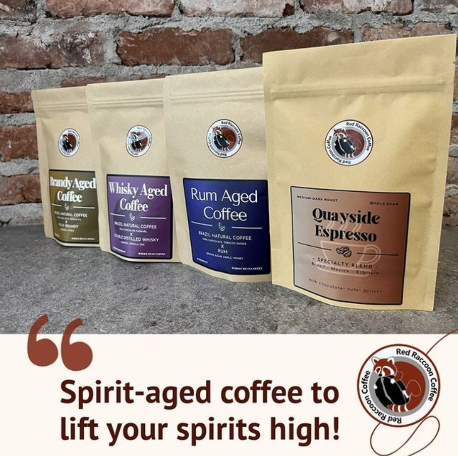 Four coffee bags on a brick wall background with the text “Spirit-aged coffee to lift your spirits high!”