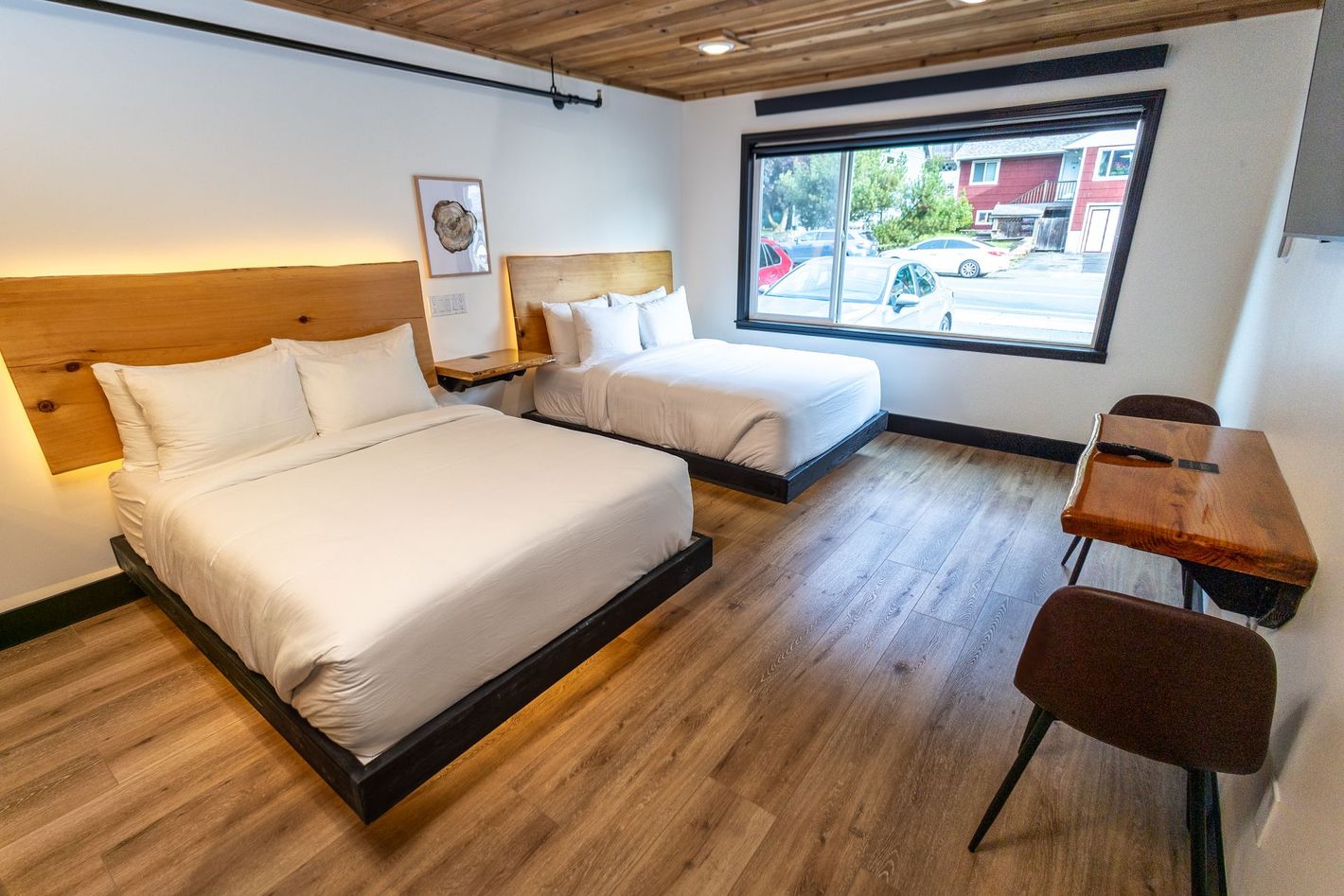 A hotel room with two beds , a desk and a window.