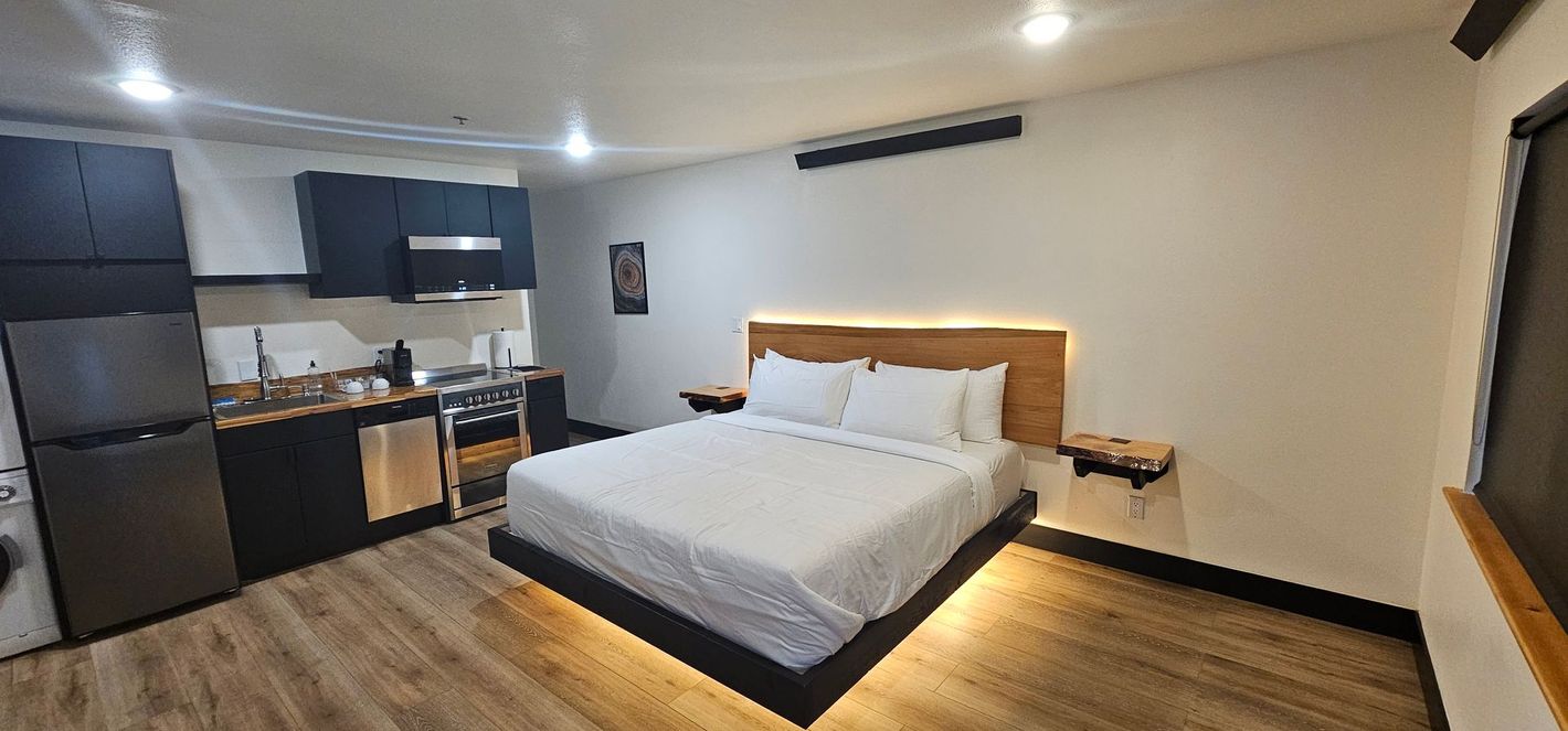 A hotel room with a king size bed and a kitchen.