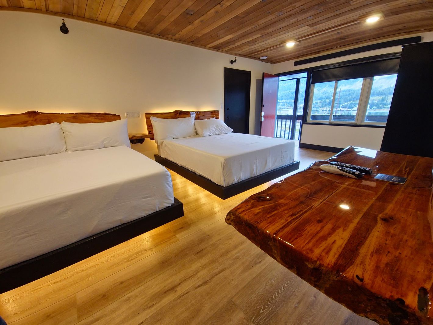 A hotel room with two beds and a wooden table.
