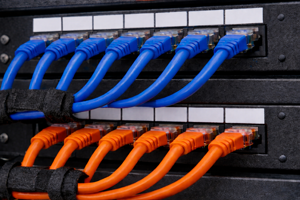 Blue and orange Ethernet cables plugged into a network switch in a server rack