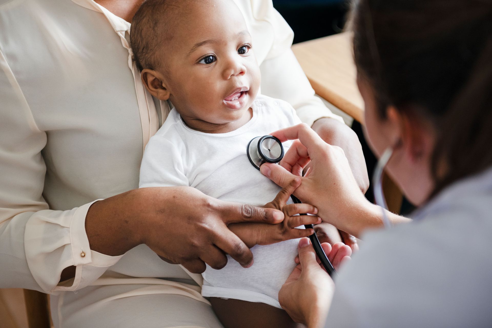 Um bebê está sendo examinado por um médico com um estetoscópio.