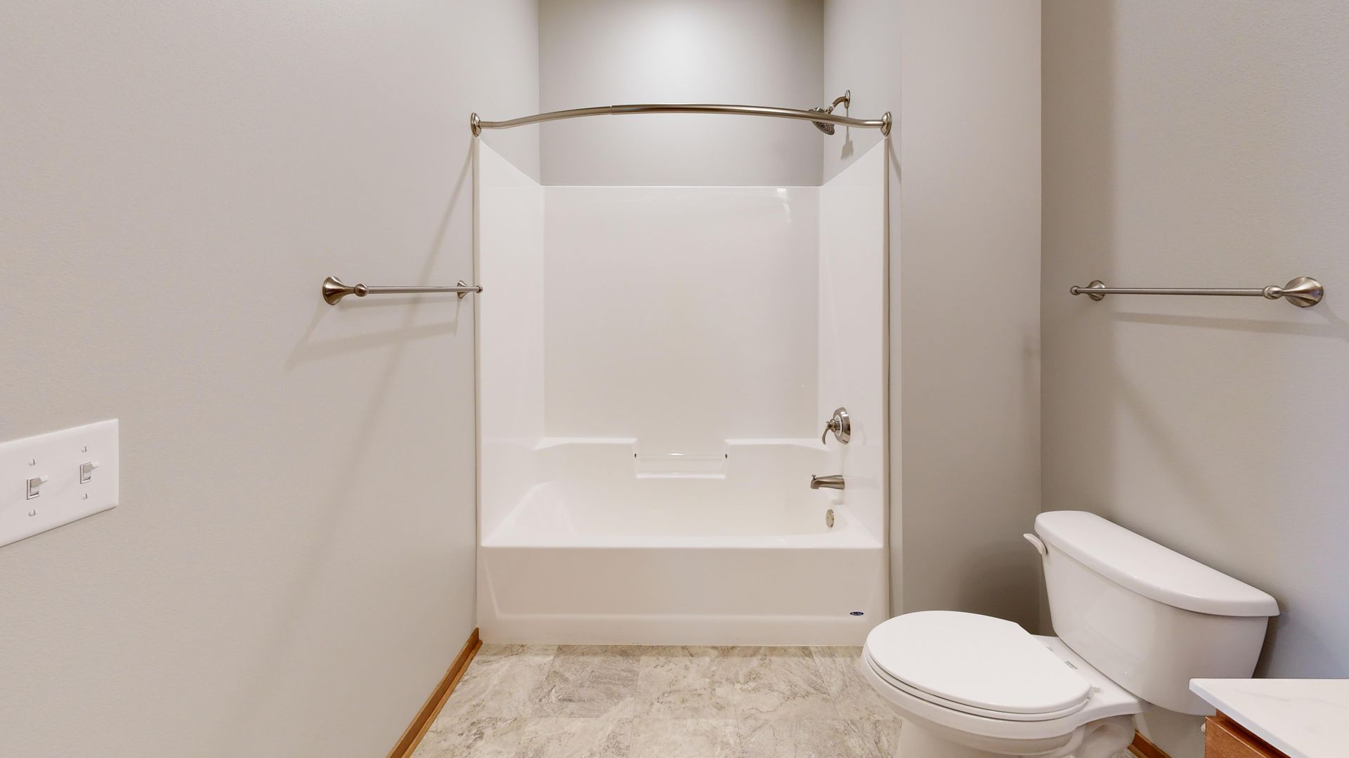 Accessible bathroom with toilet, grab bars, and walk-in shower area with white walls.