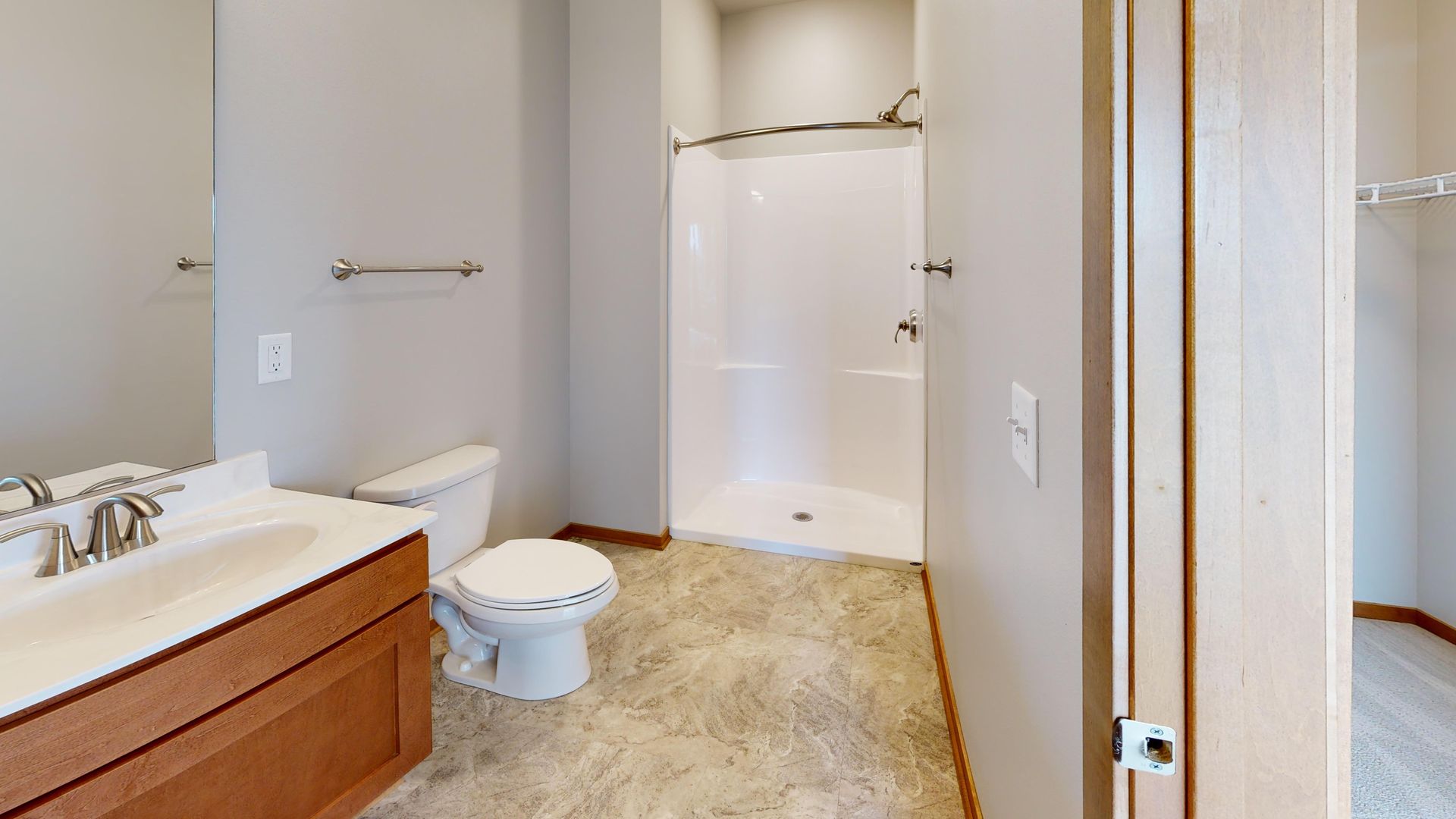 Bathroom with white tub, toilet, vanity, and beige tile floor near a doorway.