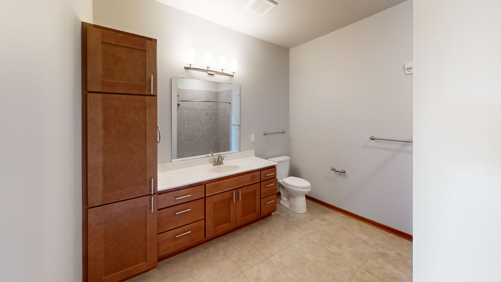 Bright bathroom with wood vanity, large mirror, toilet, and shower curtain rod against white walls.