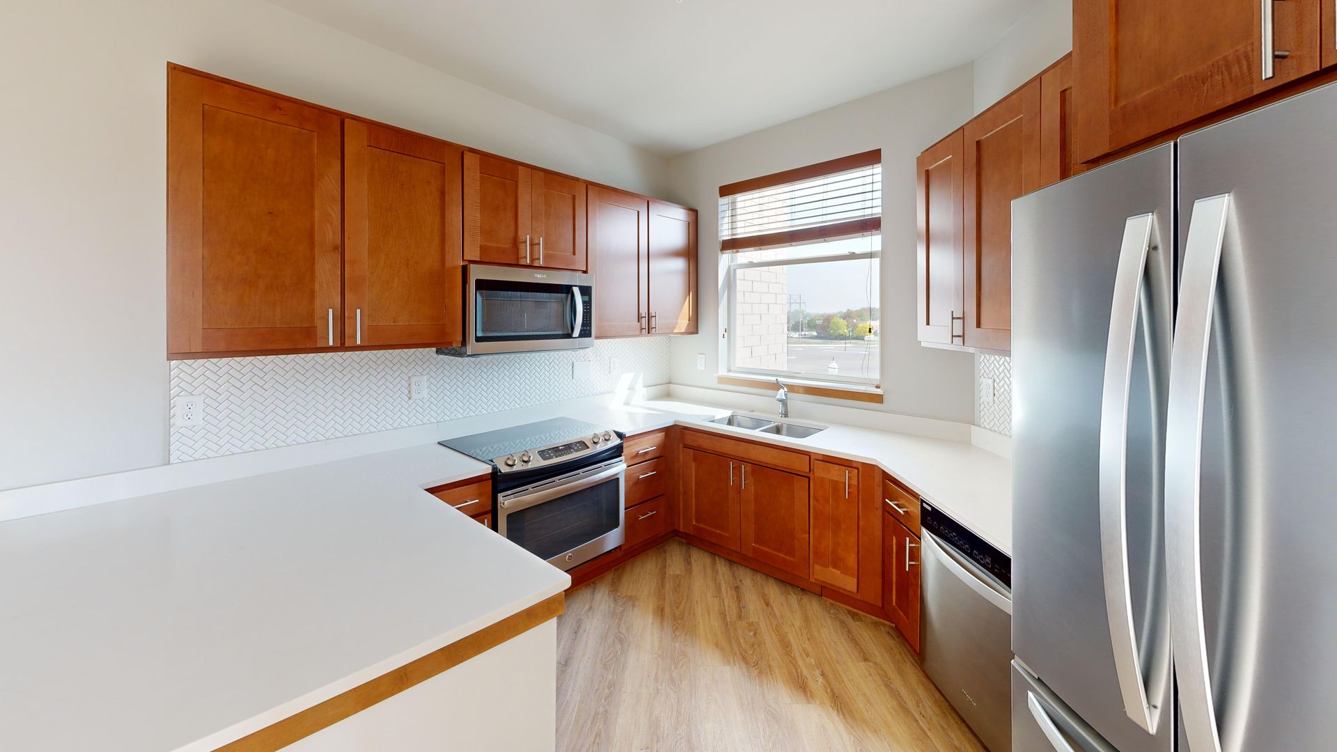 Bright modern kitchen with wooden cabinets, stainless steel appliances, and a window over the sink
