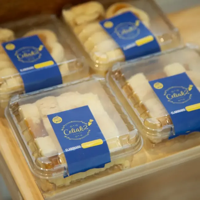 Cajas de pasteles con etiquetas azules dispuestas en una bandeja, que contienen postres cuidadosamente empaquetados.