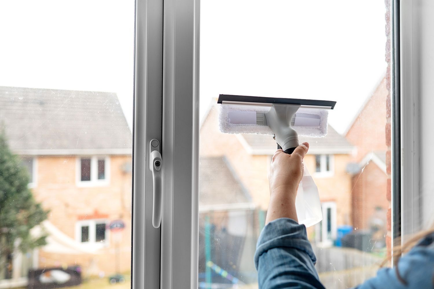 Person cleaning a window with a squeegee, seen from inside a house. Person cleaning a window with a squeegee, seen from inside a house.