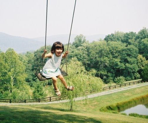 A little girl is swinging on a swing in a park