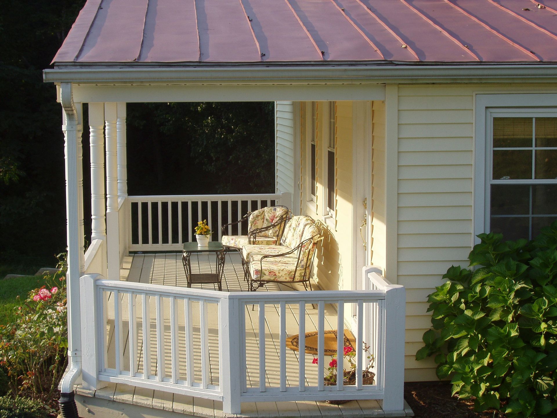 A white house with a pink roof and a porch