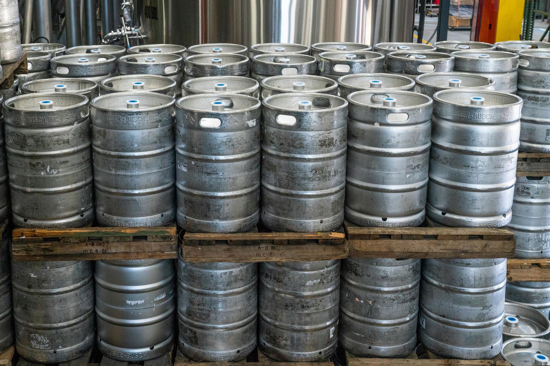 A bunch of kegs are stacked on top of each other on wooden pallets.
