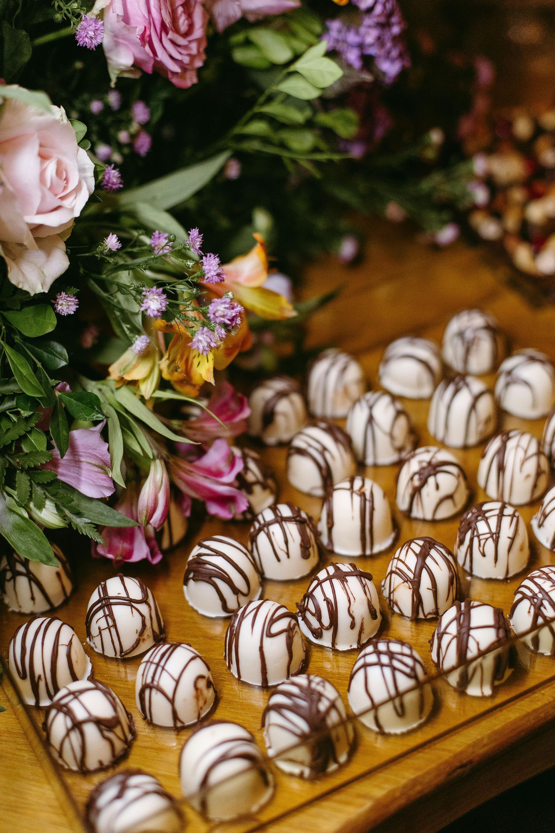 A wooden table topped with chocolate covered candies and flowers.
