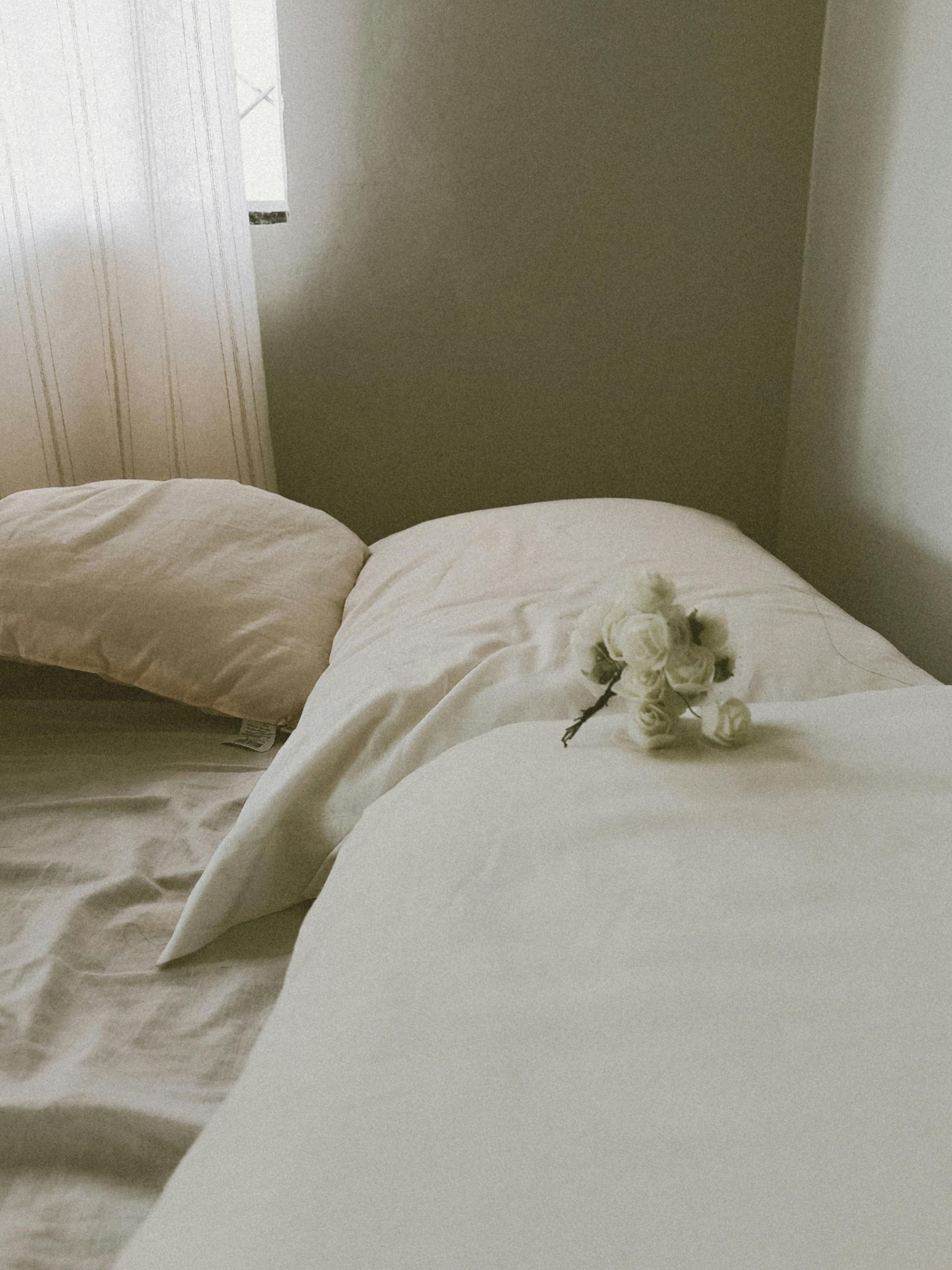 A bed with white sheets and pillows and a stuffed animal on it
