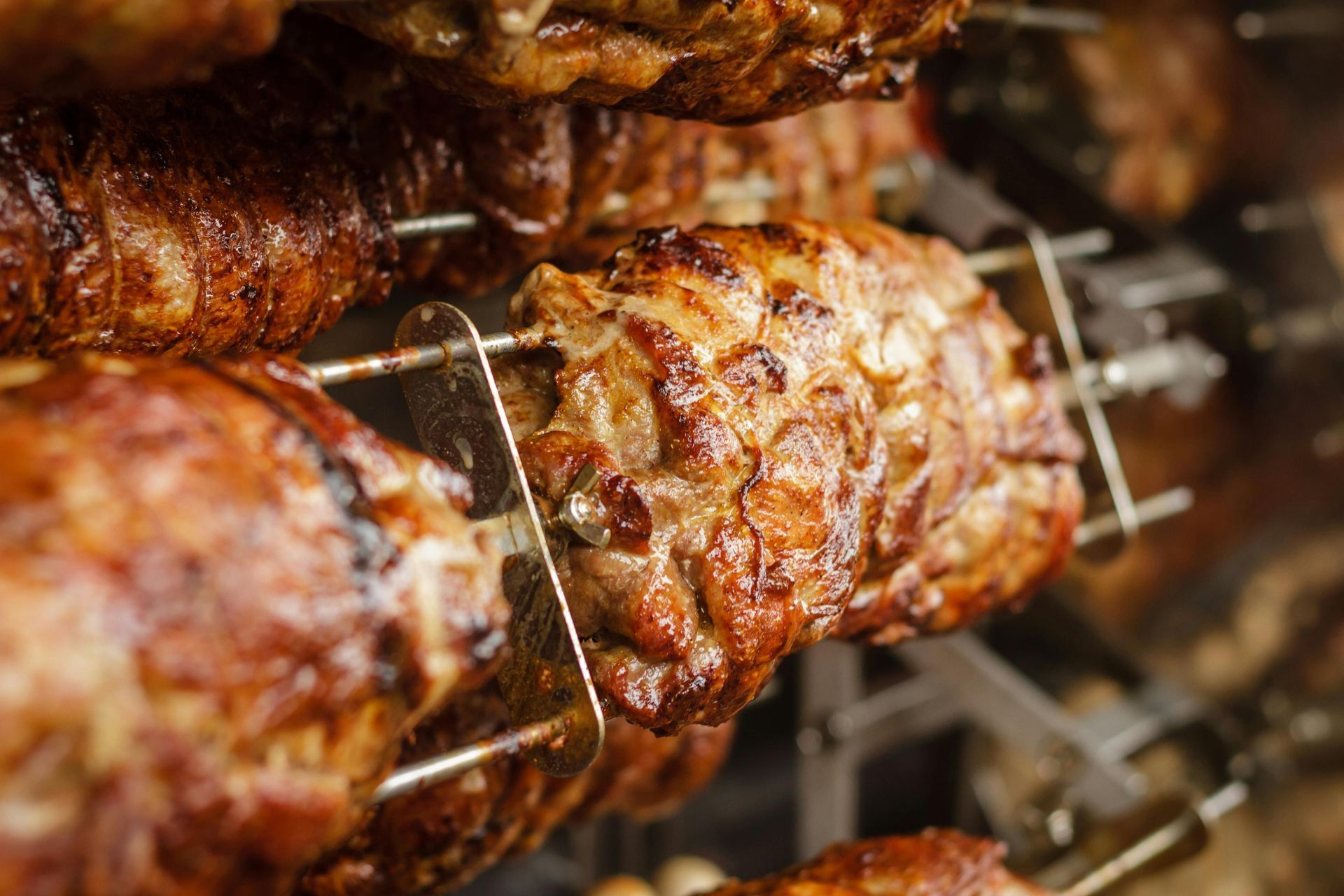 A close up of roasted chicken on skewers on a grill.