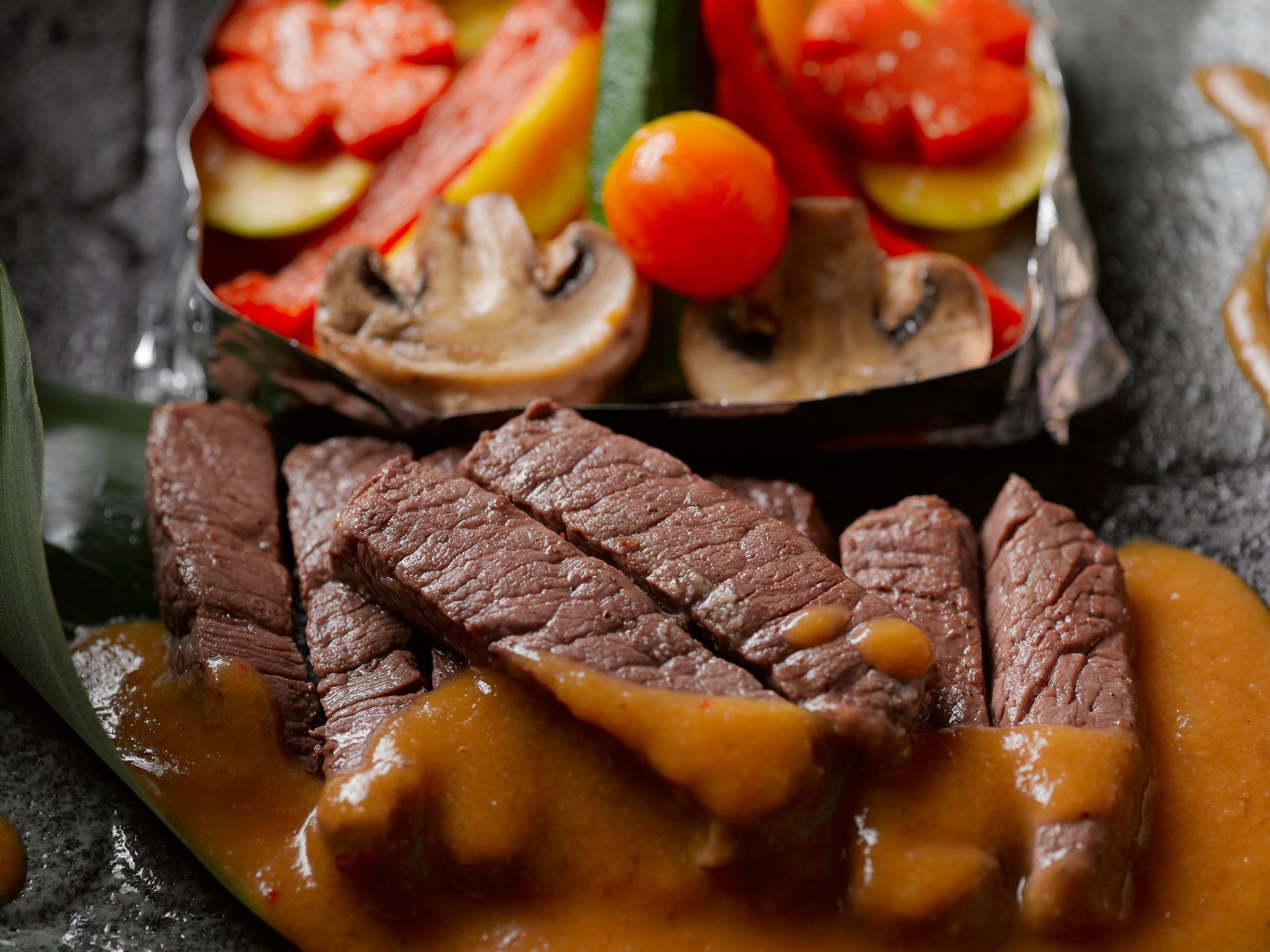 A close up of a plate of food with meat and vegetables on a table.