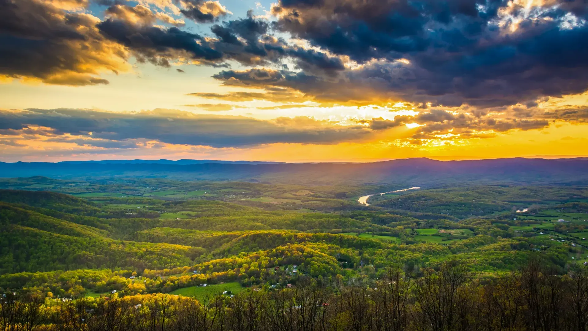 A sunset over a valley with mountains in the background