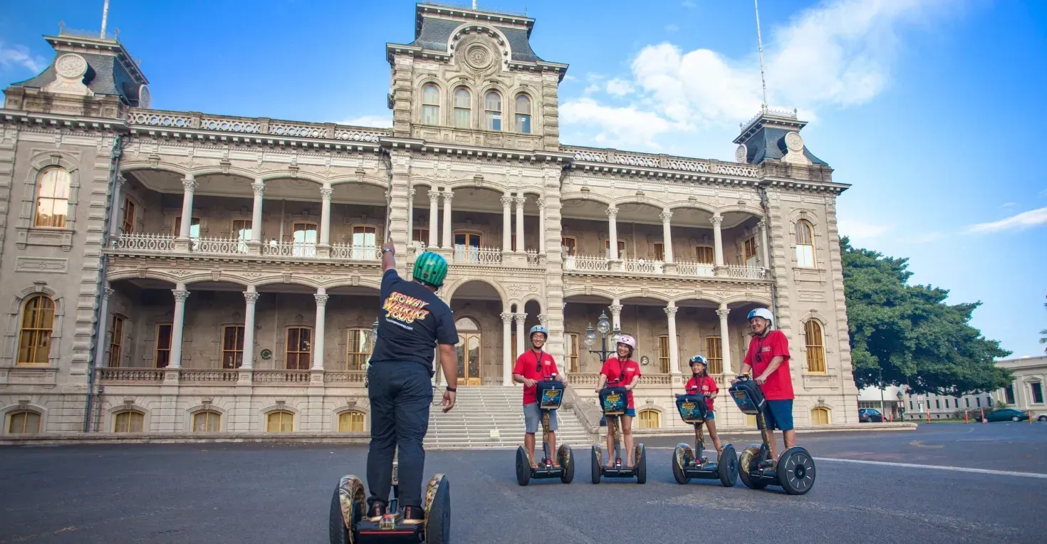 People on Segways in front of a grand historic building under a blue sky