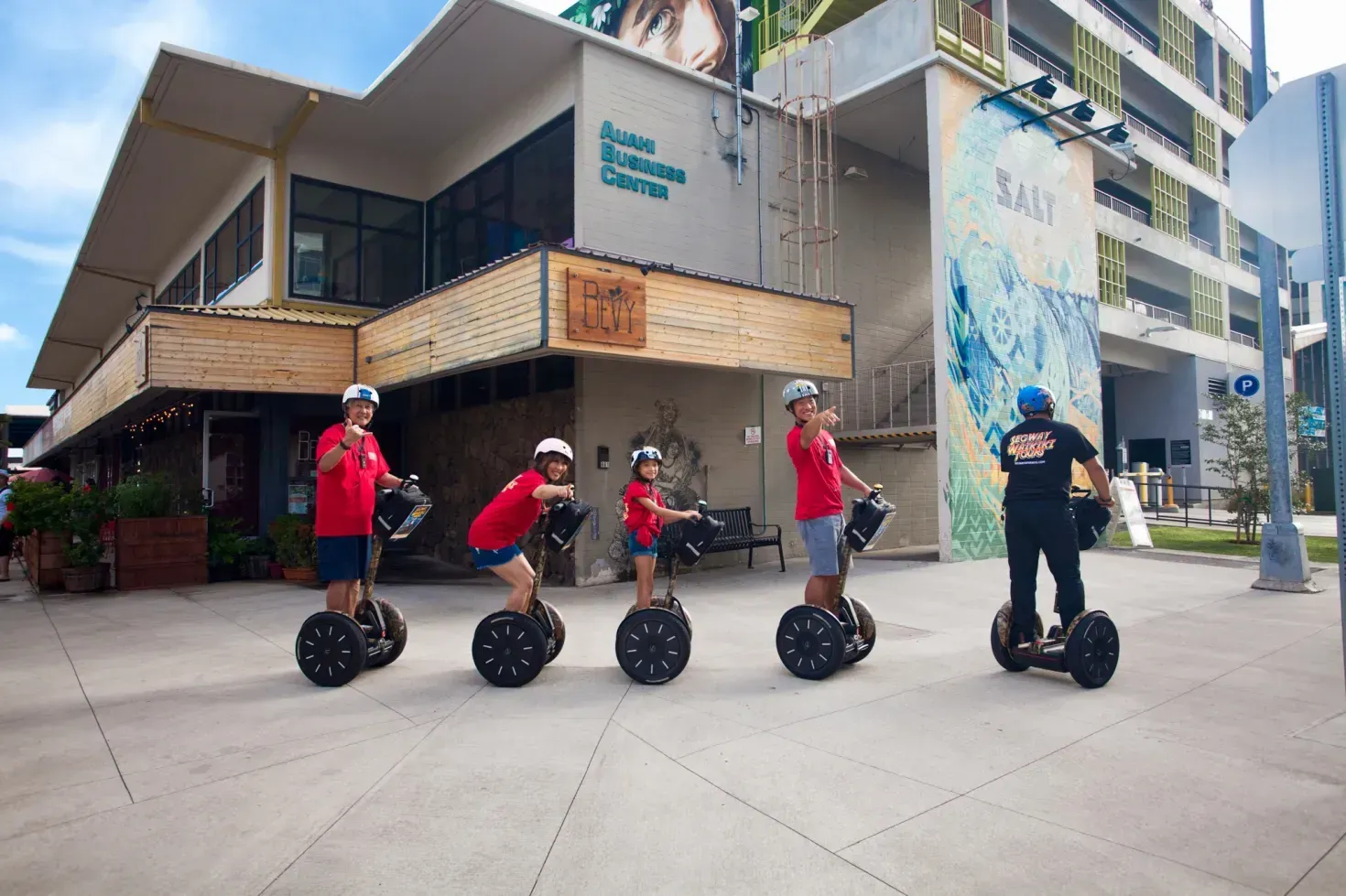 People in red shirts riding Segways outside a modern building
