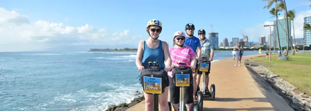 Cyclists riding along a sunny seaside boardwalk beside the ocean