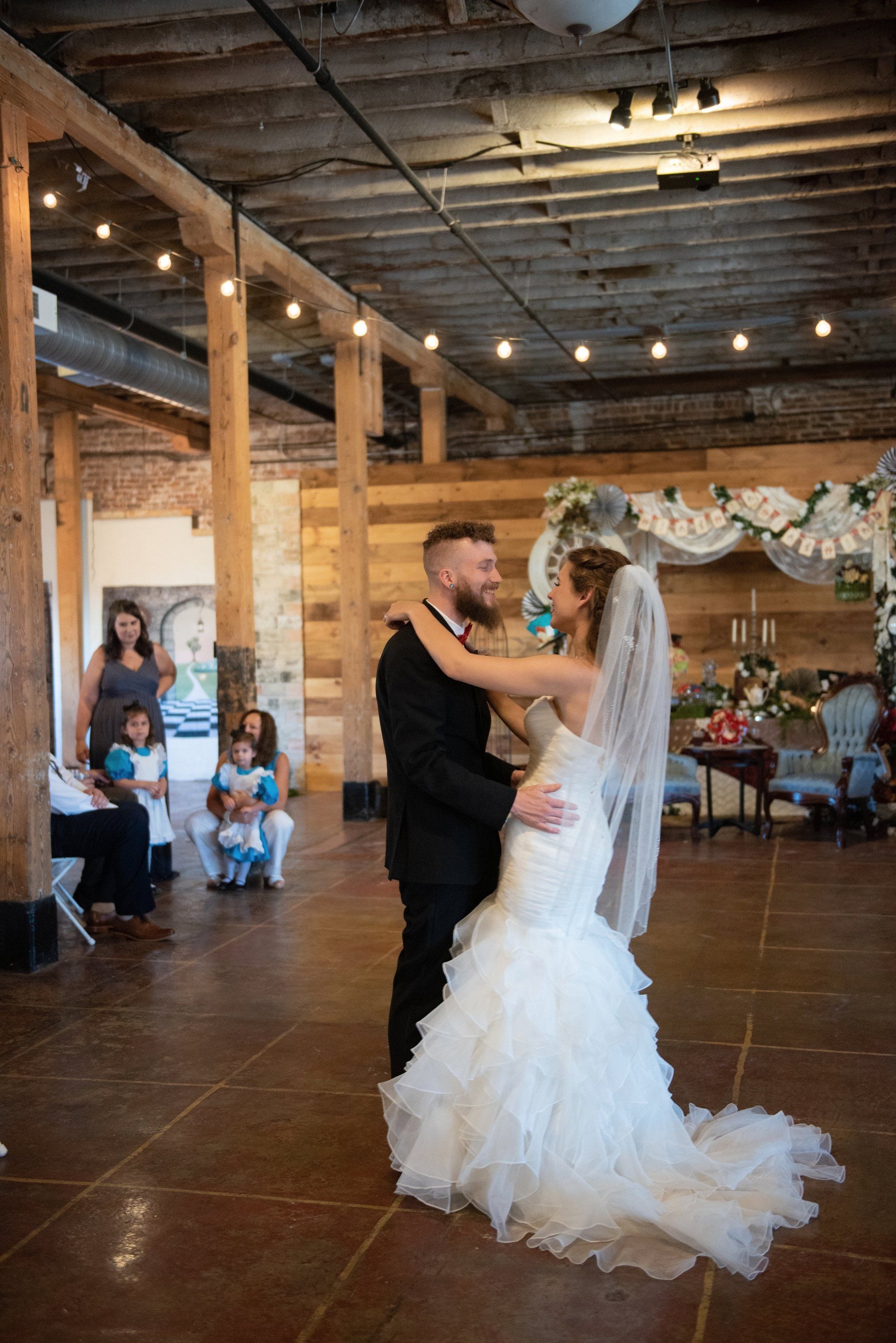 A bride and groom are dancing at their wedding reception in a large room.