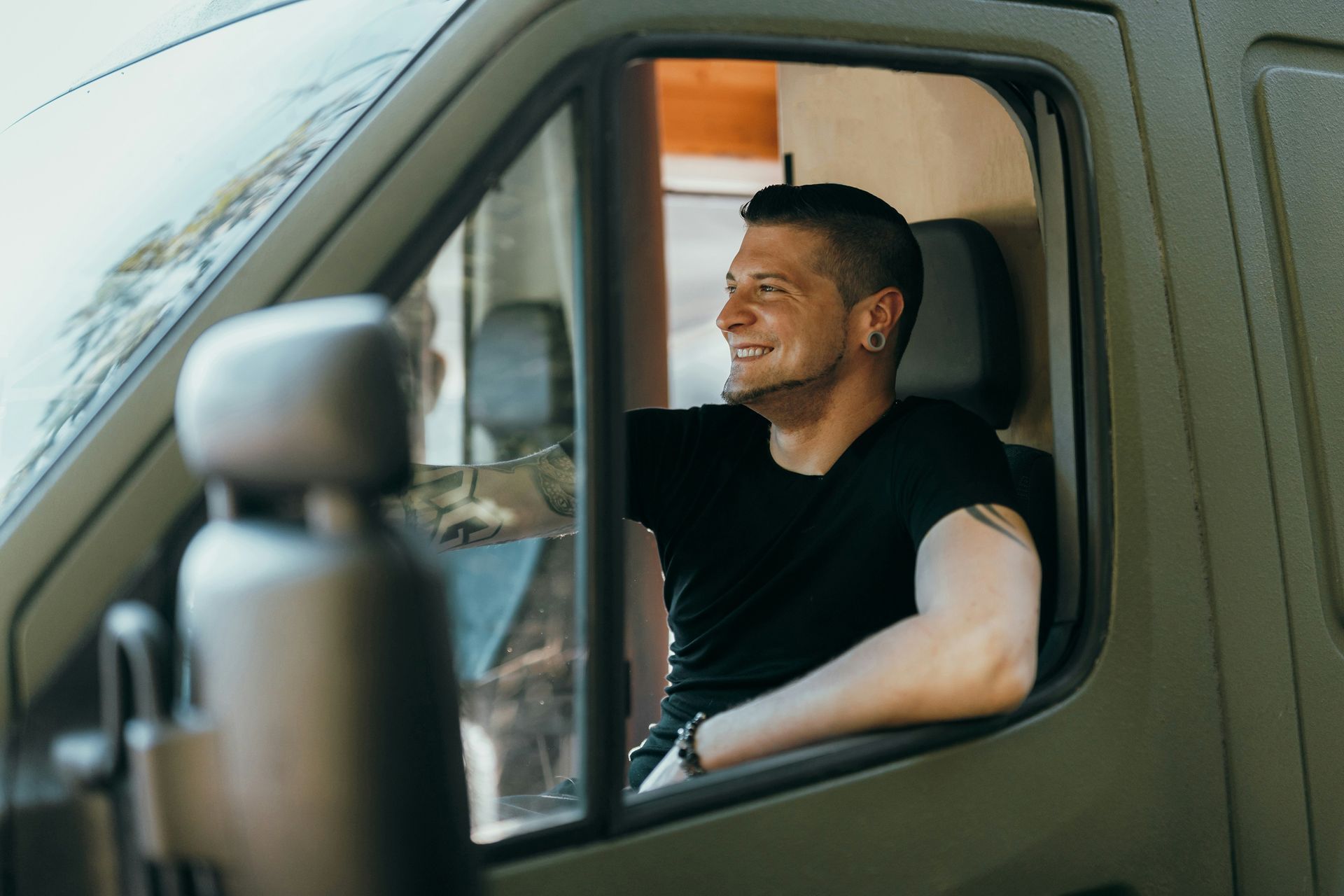 Man smiling while sitting in the driver's seat of a green van.