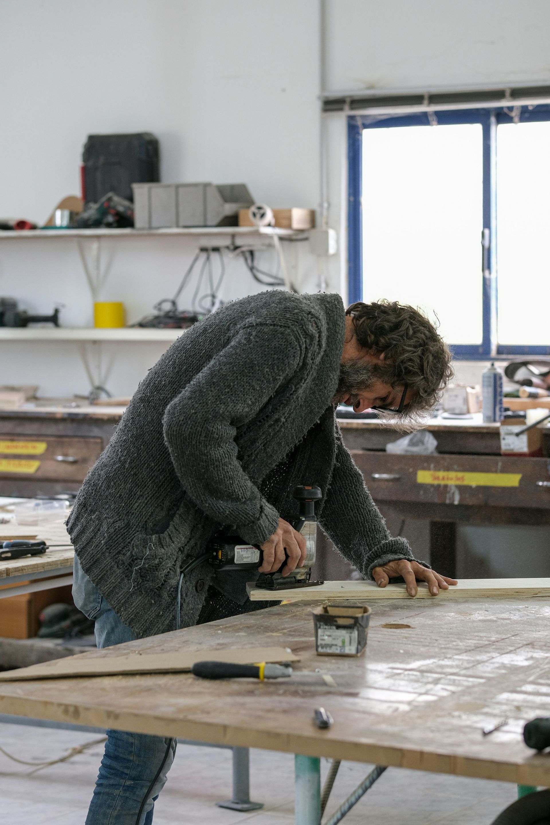 Person using a power tool to work on a piece of wood in a workshop.