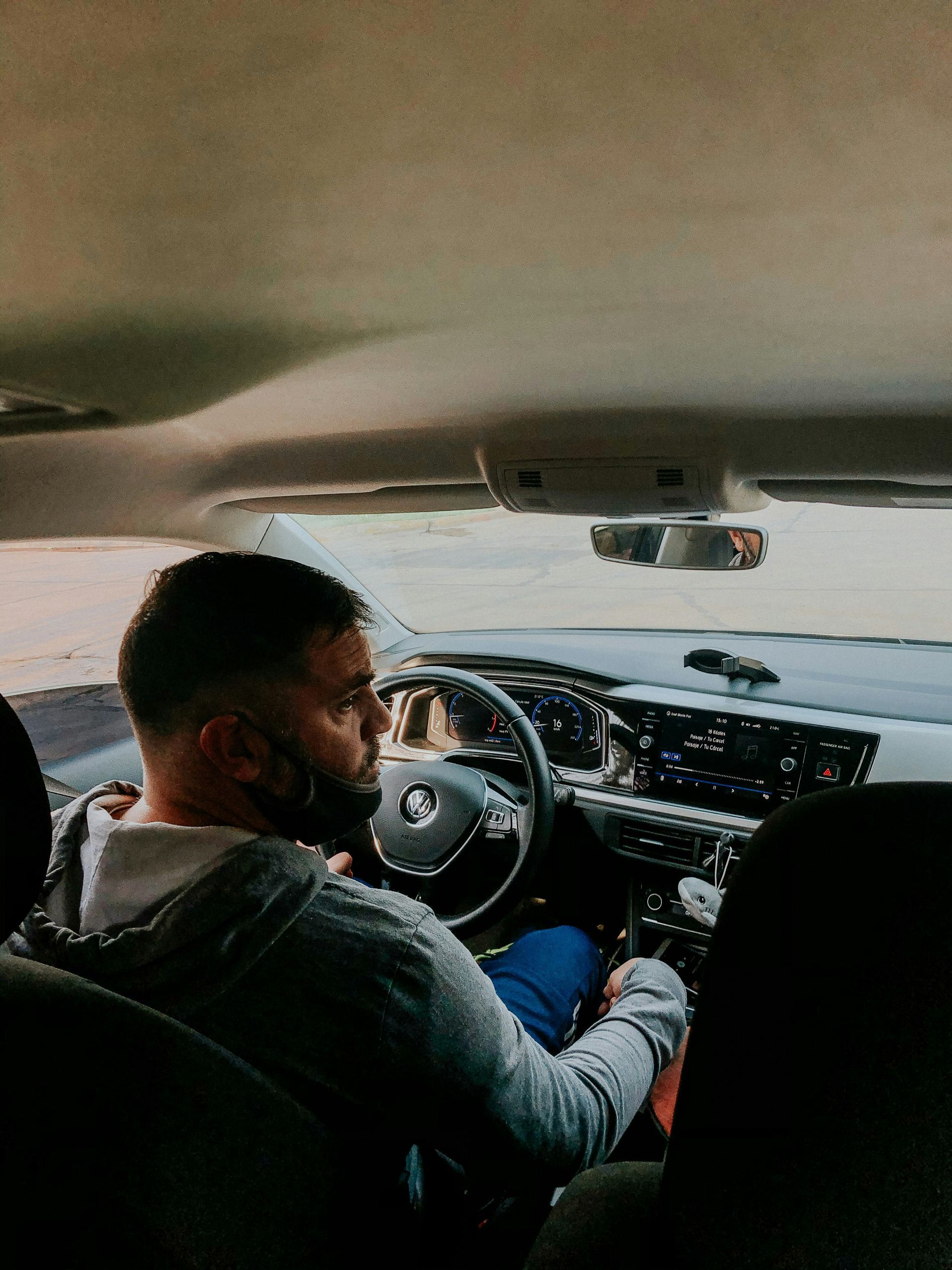 Man driving a car, hands on the steering wheel, looking forward.