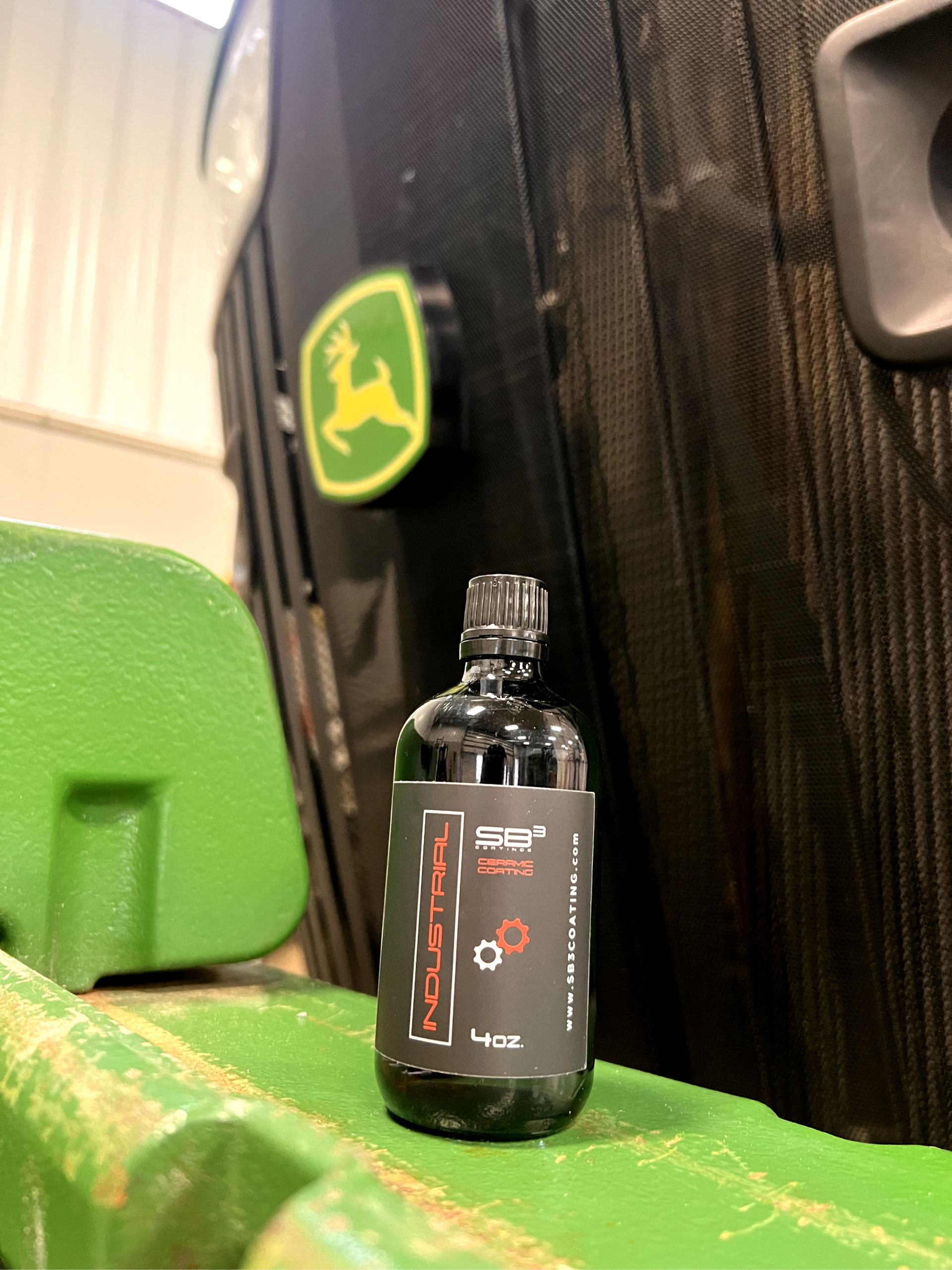 A bottle of liquid is sitting on a green chair in front of a john deere logo.