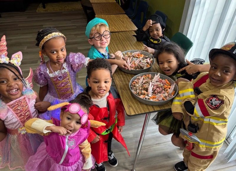 Children in colorful costumes smiling around a table with snacks at a party