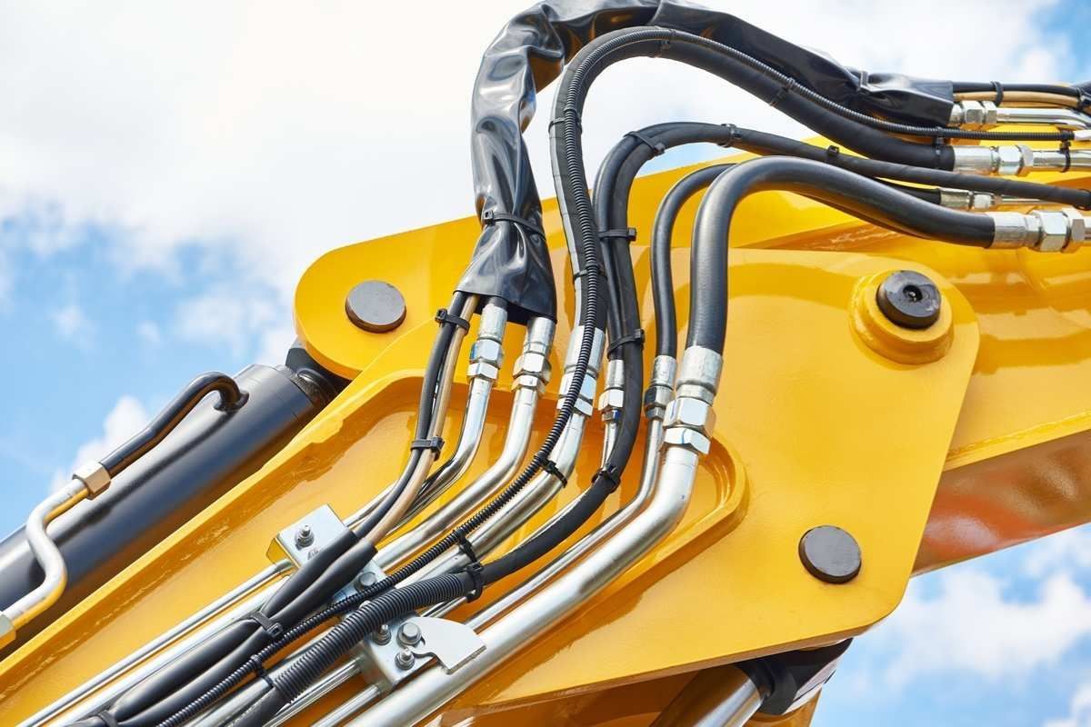 Primo piano di un escavatore giallo con tubi idraulici collegati.