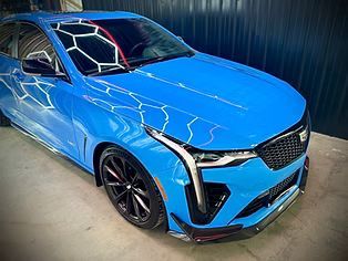 Blue Cadillac SUV parked indoors with a smashed windshield and visible front-end damage