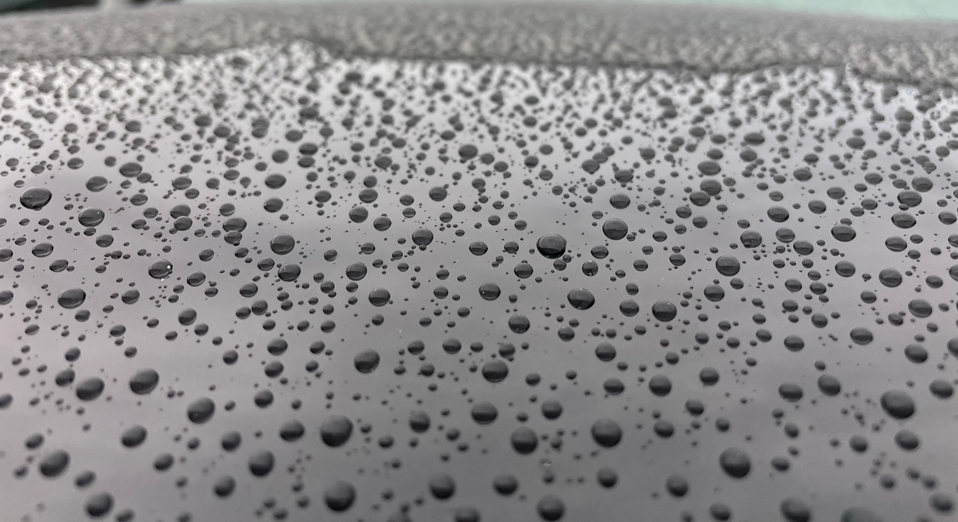 Close-up of raindrops on a gray car surface