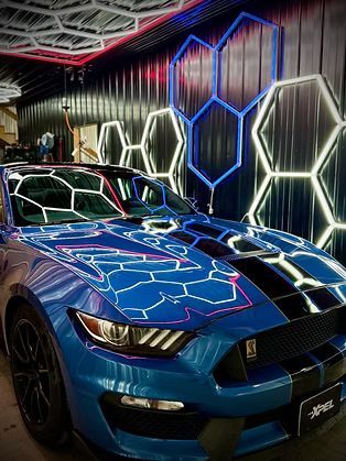 Blue sports car with white neon reflections in a modern showroom with hexagonal wall lights