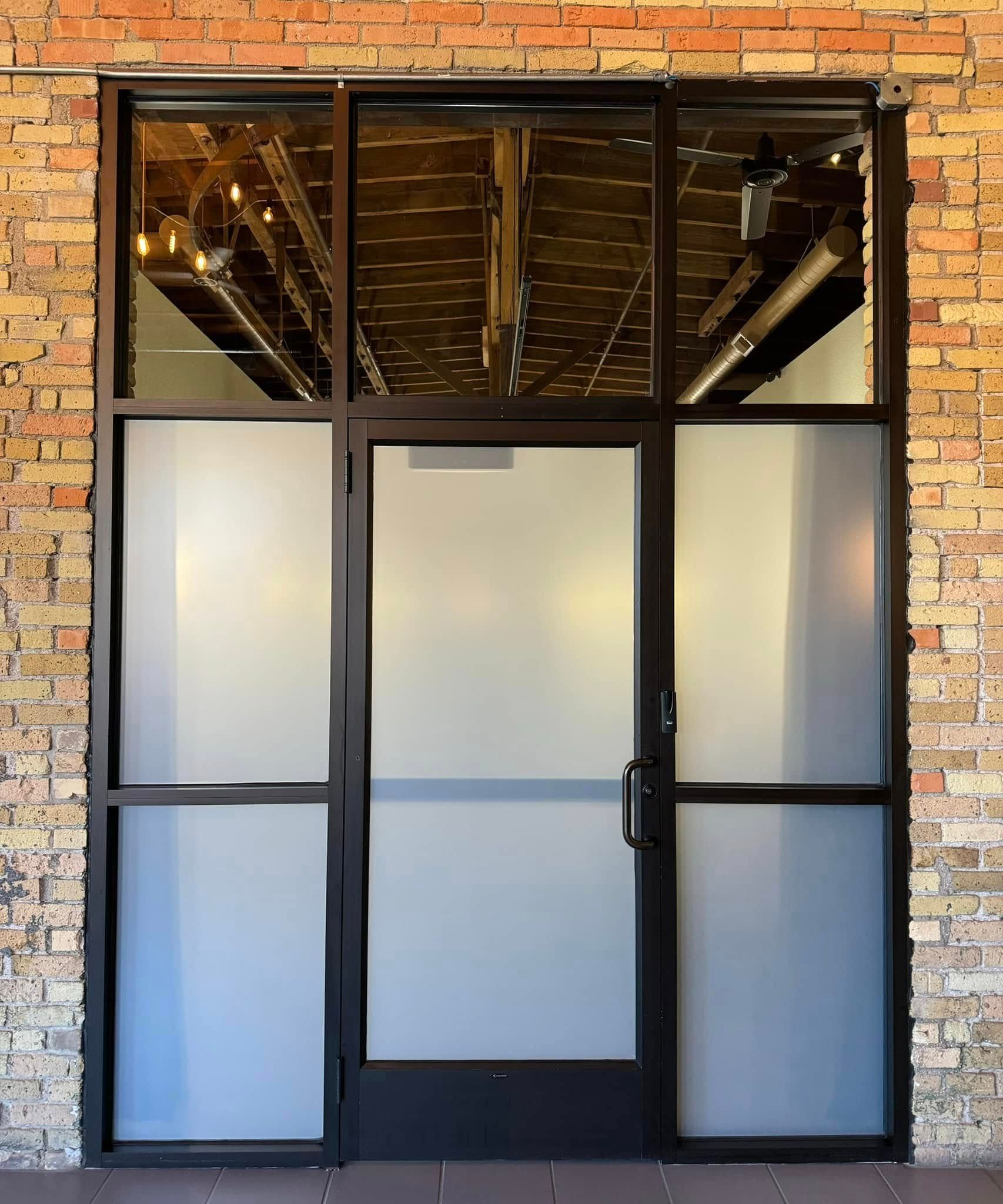 Brick storefront entrance with frosted glass double doors and transom windows