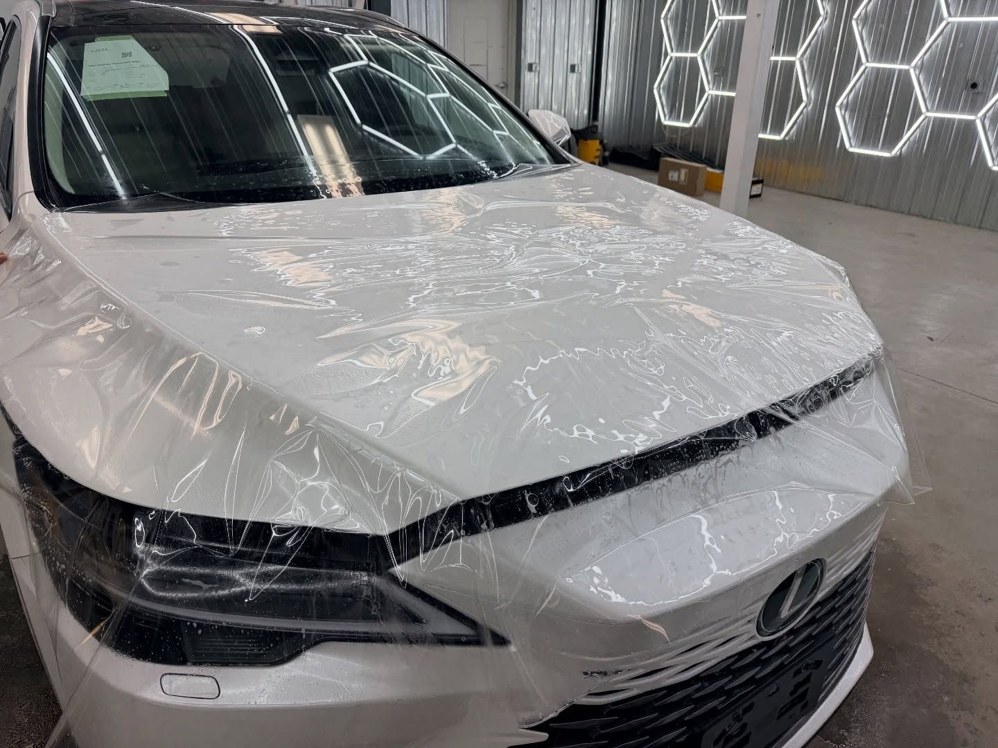 White SUV covered in plastic wrap inside a car wash or detailing bay