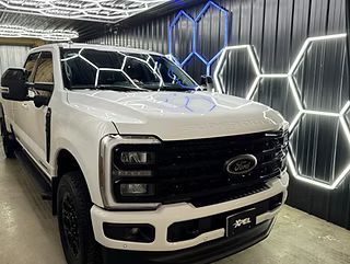 White Ford pickup truck in a showroom with geometric neon wall lights