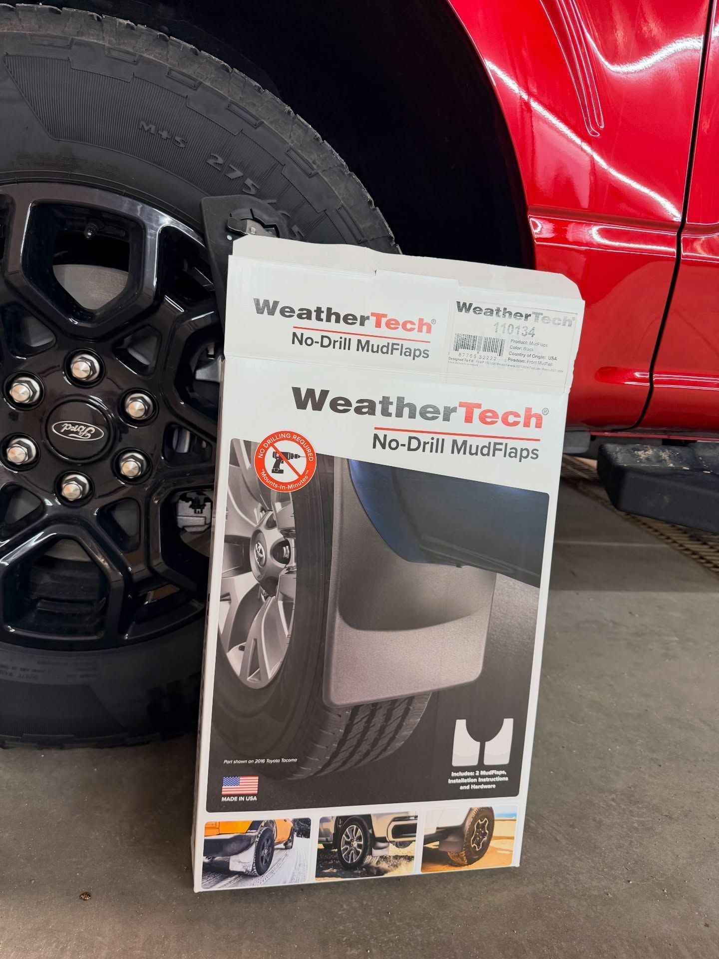 WeatherTech No-Drill MudFlaps box beside a black wheel on a red vehicle