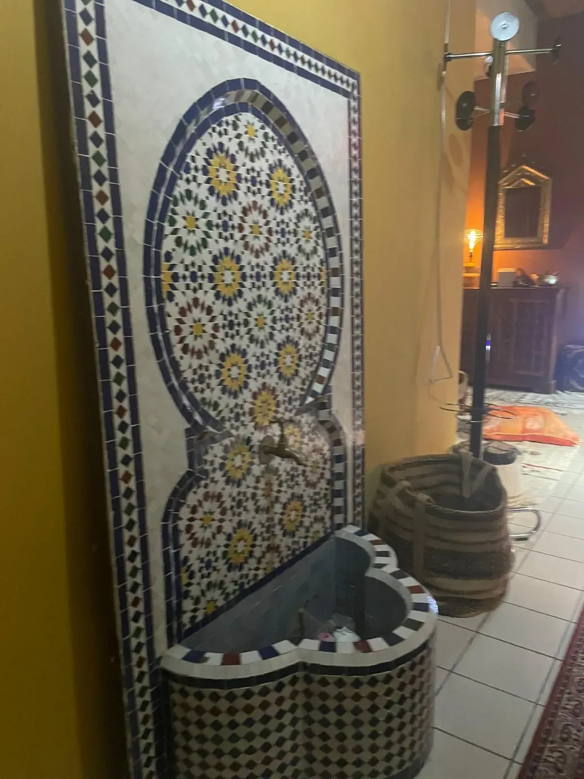 Fontana decorata con mosaici e parete piastrellata all'interno di un caffè o di un cortile.