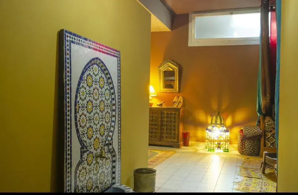 Un accogliente corridoio giallo con decorazioni murali, lanterne e pavimento piastrellato, crea un'atmosfera intima e confortevole.