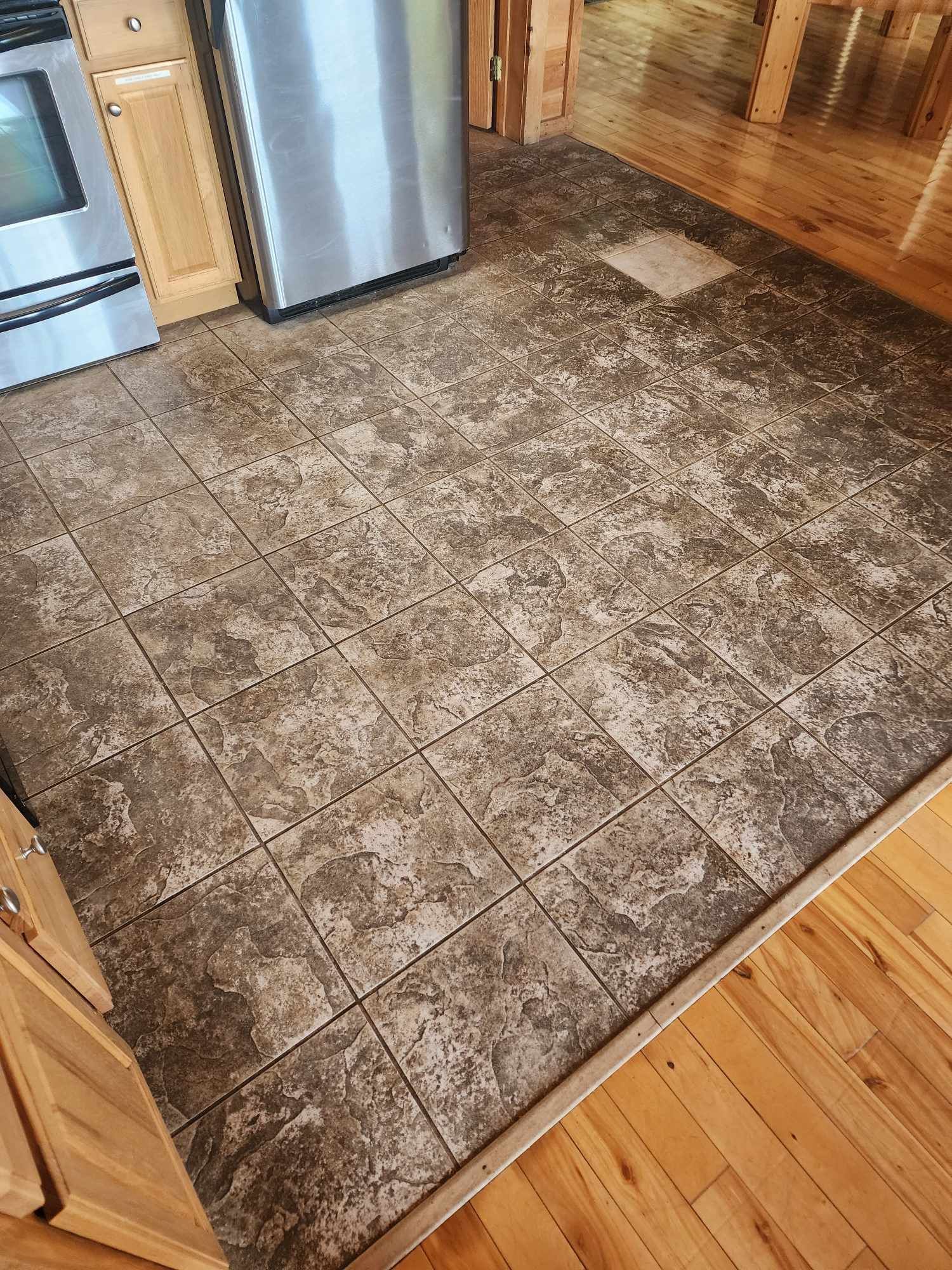 A kitchen with a tile floor and a stainless steel refrigerator.