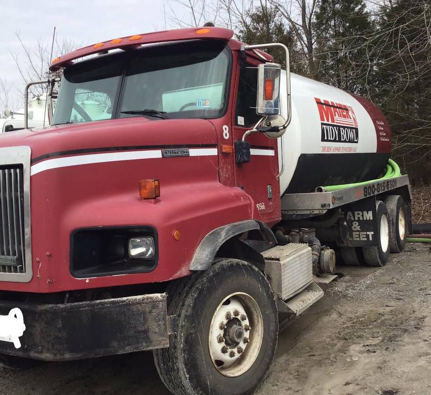 Red and white cement mixer truck parked on a dirt lot