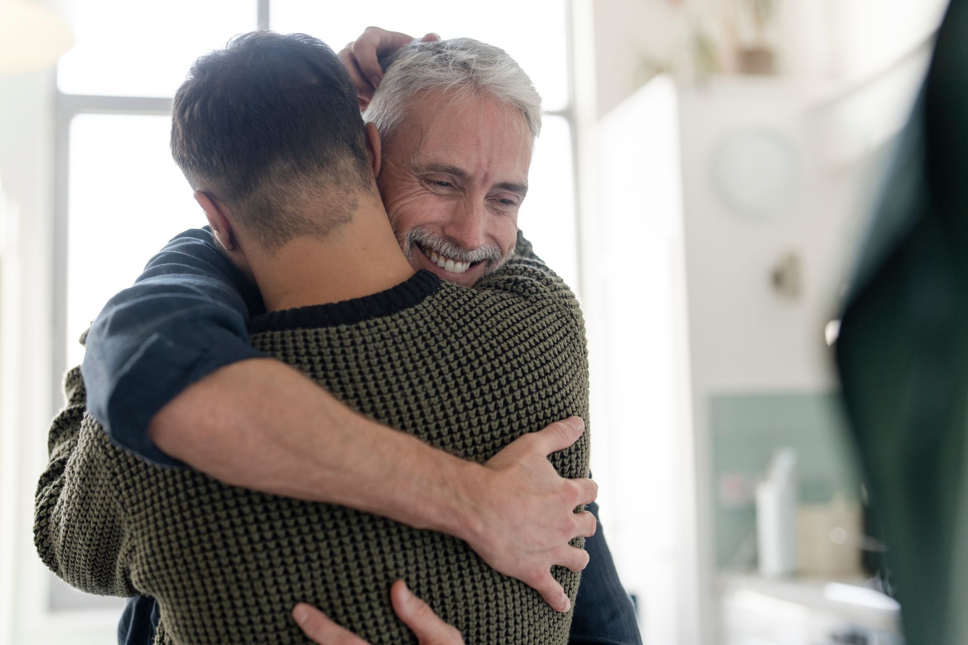 two people embracing indoors, showing a close, comforting hug.