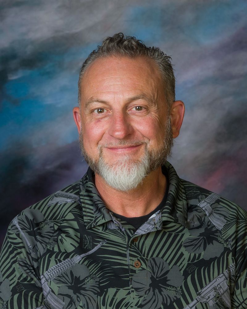 A man with a beard and a green shirt is smiling for the camera.