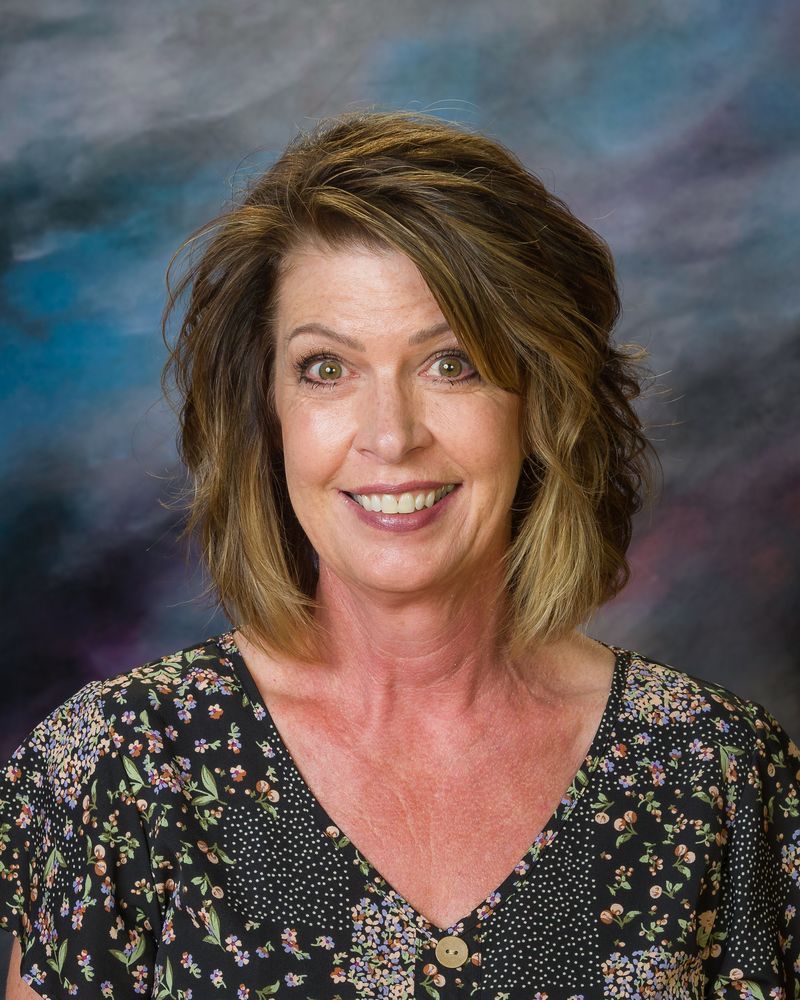 A woman in a floral shirt is smiling for the camera.
