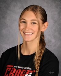 Portrait of a smiling athlete in a black shirt with a side braid against a gray studio backdrop