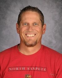 Smiling man in a red shirt against a gray studio backdrop