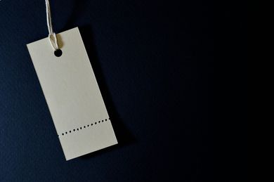 Off-white price tag hanging from a string, set against a dark blue background.