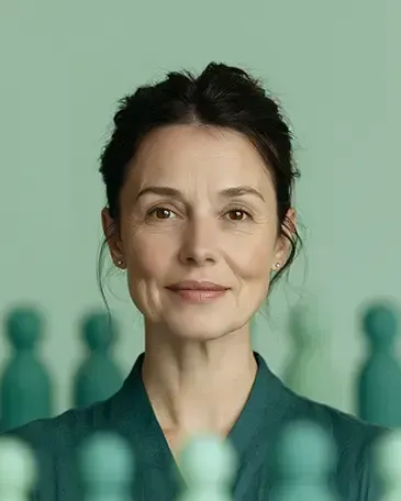 Portrait of a woman in a teal top, centered against a pale green background with blurred chess pieces in front and back of her.