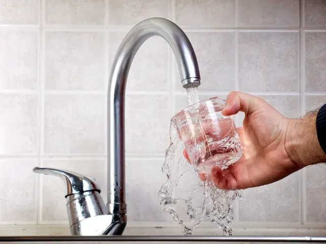 une personne verse de l' eau dans un verre dans un évier .