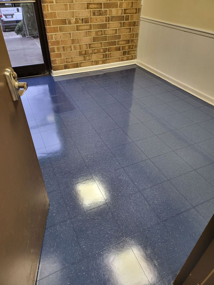 An empty room with blue speckled flooring and brick and white walls. The door is open.